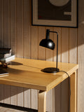 Finn Juhl FJ Elements black table lamp by Louis Poulsen on wood desk, focused task lighting for home office.