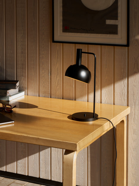 Finn Juhl FJ Elements black table lamp by Louis Poulsen on wood desk, focused task lighting for home office.