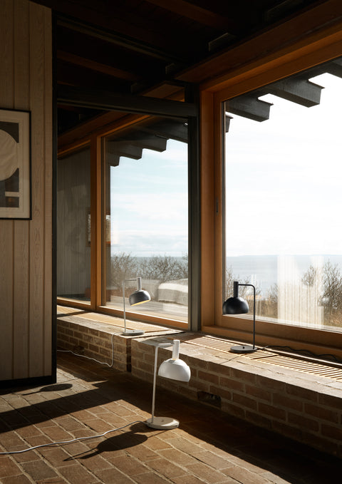 Finn Juhl FJ Elements modern table lamp by Louis Poulsen in white, grey and black on windowsill, modern Scandinavian desk lighting.