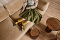 Woman in olive skirt seated on Sunday 82" Sofa by Blu Dot in Camel Velvet