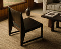 Frama Easy Chair 01 in Dark Brown Birch, dark low chair on a sisal rug in a wood panelled room with a ceramic jug and low table