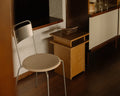 Frama Ratio Side Table in Warm Brown Birch, table beside a metal chair with a round seat, a stone tray on top and a dark sideboard behind