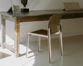 Frama Rivet Chair in Aluminum, metal chair tucked under a rough stone topped table in a bright room with raking sunlight