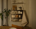 Frama Shelf Library Canvas Cabinet in Stainless Steel and Canvas, canvas folded back on a kitchen shelf unit with stacked plates and cups