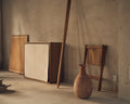 Frama Shelf Library Canvas Cabinet in Natural Oak and Canvas, canvas fronted cabinet leaning on a plaster wall beside a clay vase and a folding chair