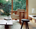 Frama Symmetry Lounge Chair in Oat Fabric and Ash, two chairs by a window with ivy outside, a low table and a dark round stool on a shaggy rug