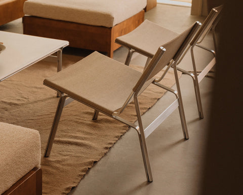 Frama Union Easy Chair in Sandstone Linen and Aluminum, two chairs on a woven rug beside upholstered seating and a low white table