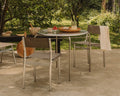 Frama Union Chair in Sandstone Mesh and Aluminum, four chairs around a round garden table laid with bowls and fruit under trees