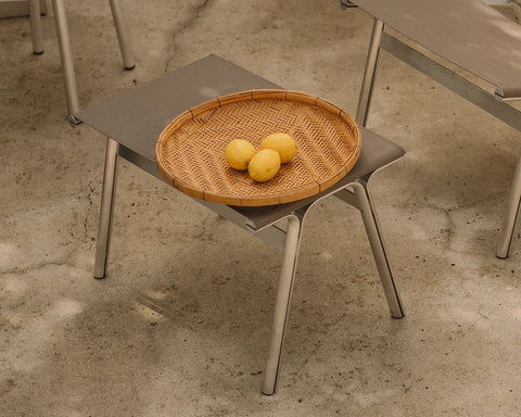 Frama Union Stool in Taupe Mesh and Aluminum, stool on a concrete floor holding a woven tray of lemons, seen from above