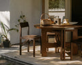 Frama Bracket Chair in Dark Brown Ash, dark ash chair on a jute rug beside a round wooden table holding a basket and a jug