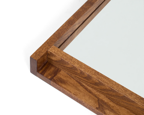 Frama Symmetry Mirror, close up of the frame corner showing the grain of the brown wood and the lipped edge that holds the glass