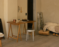 Frama Folding Flat Trestle Table in Warm Brown Birch, birch trestle table used as a desk in a plaster room with a stool and a ladder