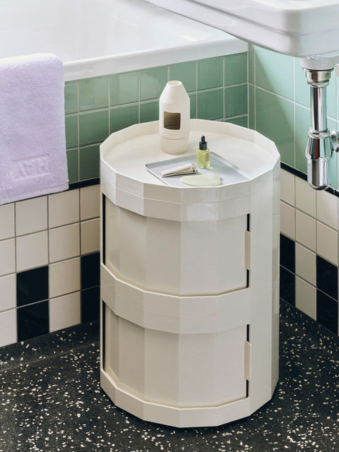 HAY Chim Chim Scent Diffuser, Light Beige, ceramic tealight scent diffuser, on a cream cabinet in a green tiled bathroom with an oil bottle