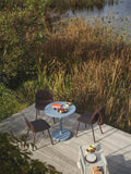 outdoor lifestyle image of chairs and round table by the pond with furniture from muuto 