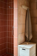 Form & Refine A Line Laundry Box, solid oak laundry hamper, white oak laundry box in a shower room with terracotta tiles and a linen towel