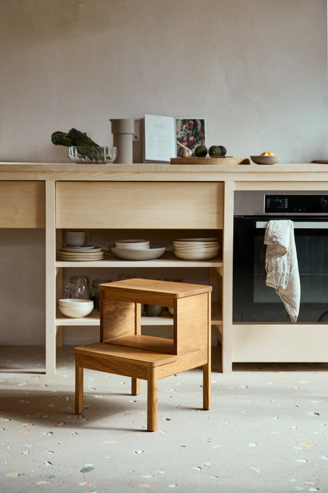 Form & Refine A Line Stepstool, solid oak step stool, oak step stool in a kitchen beside an oak cabinet with dishes and bowls