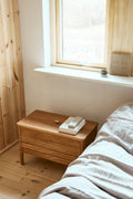 Form & Refine A Line Storage Bench 68, oak storage bench with lid, oak storage bench at the foot of a bed beneath a window in a pine-clad room