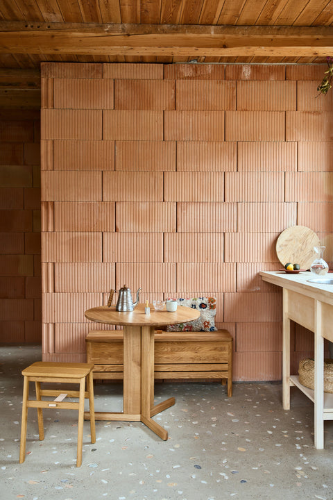 Form & Refine Angle Foldable Stool, folding oak stool, oak foldable stool at a round table in a kitchen with a terracotta tiled wall