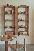 Form & Refine Beam Shelf 5, solid pine wall shelf, two pine shelves holding bowls and glassware above a round table and a chair