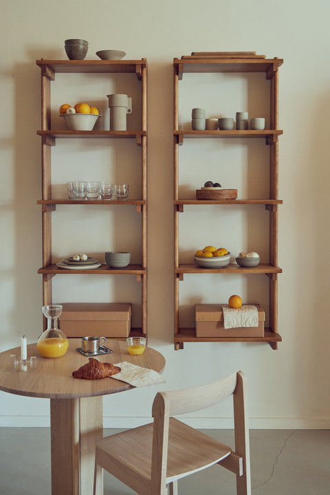 Form & Refine Beam Shelf 5, solid pine wall shelf, two pine shelves holding bowls and glassware above a round table and a chair