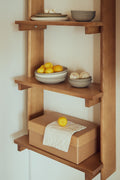Form & Refine Beam Shelf 5, solid pine wall shelf, deep brown pine shelf holding bowls of lemons and a wooden box with a linen cloth