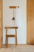 Form & Refine Echo Coat Rack 40, solid oak wall coat rack, oak coat rack with a linen shirt and dustpan above a Lunar chair beside a front door