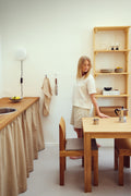 Form & Refine Element Table 70x70, square oak dining table, person at the oak square table with a Sonder chair in a kitchen with a pine shelf