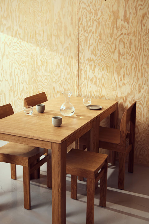 Form & Refine Element Table 70x70, square oak dining table, oak square table set with cups and Sonder chairs against a plywood wall