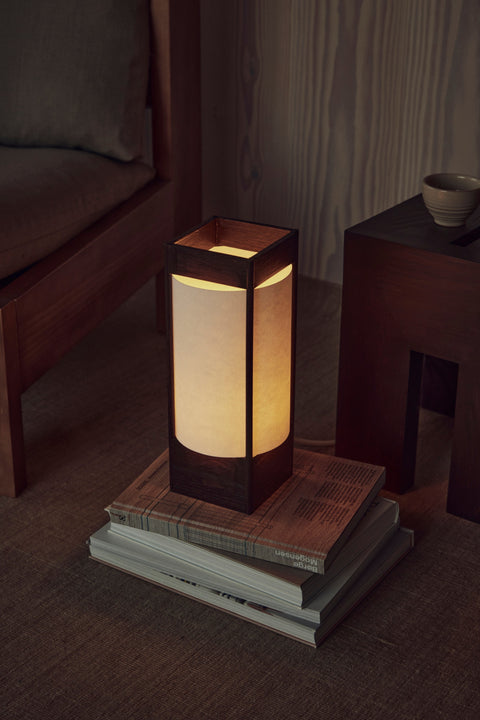 Form & Refine Icon Lounge Chair, solid pine lounge chair with cushions, paper lantern table lamp on a stack of books beside the deep brown pine lounge chair