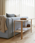 Form & Refine Leaf Shelf 2x2, solid oak shelving unit, oak shelf used as a room divider behind a grey sofa with a throw and books