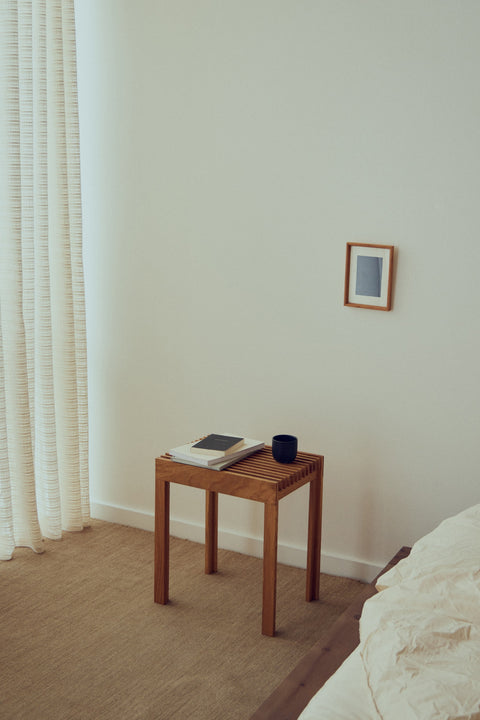 Form & Refine Lightweight Stool, solid oak stool, oak stool used as a bedside table with a book and a cup by a curtained window