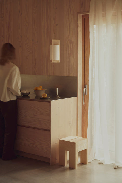 Form & Refine Monolith Side Table, solid wood side table, person at a small kitchen counter with the ash side table beside the cabinet