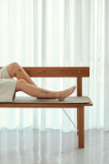Form & Refine Position Bench, solid oak bench with backrest, person lying along the oak bench with a Hallingdal cushion in front of sheer curtains