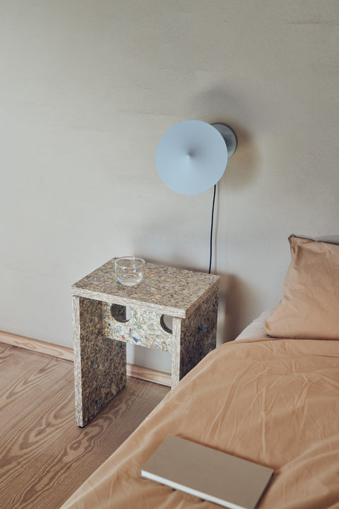 Form & Refine Remake Stool, recycled carton stool, the recycled-carton stool as a bedside table beneath a blue wall lamp