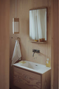 Form & Refine Rim Mirror, oak-framed wall mirror with shelf, oak-framed mirror above a basin in a plywood bathroom beside a small wall lamp