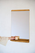 Form & Refine Rim Mirror, oak-framed wall mirror with shelf, oak-framed mirror with a hand setting a cup on its shelf
