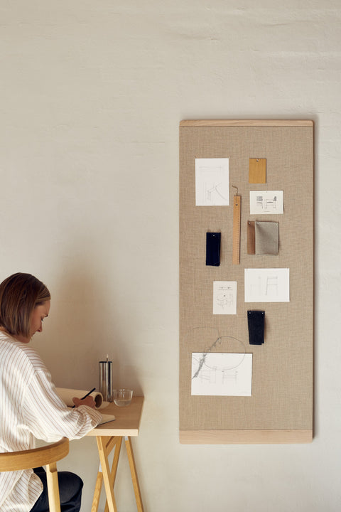 Form & Refine Rim Pinboard 60x145, tall oak-framed pinboard, person seated at a desk beneath the tall white oak pinboard with pinned notes