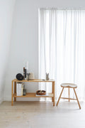 Form & Refine Shoemaker Chair™, No. 49, wooden Shoemaker stool, white oak Shoemaker stool beside a white oak Leaf Shelf in front of sheer curtains