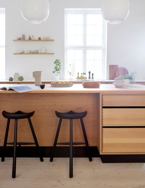 Form & Refine Shoemaker Chair™, No. 68, wooden Shoemaker stool, black Shoemaker stools at a pale oak kitchen island under pendant lamps