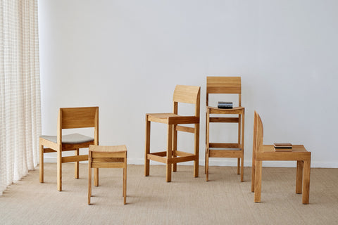 Form & Refine Sonder Chair, solid oak dining chair, the Sonder chairs, bar chairs and stool in oak grouped on a rug in a white room