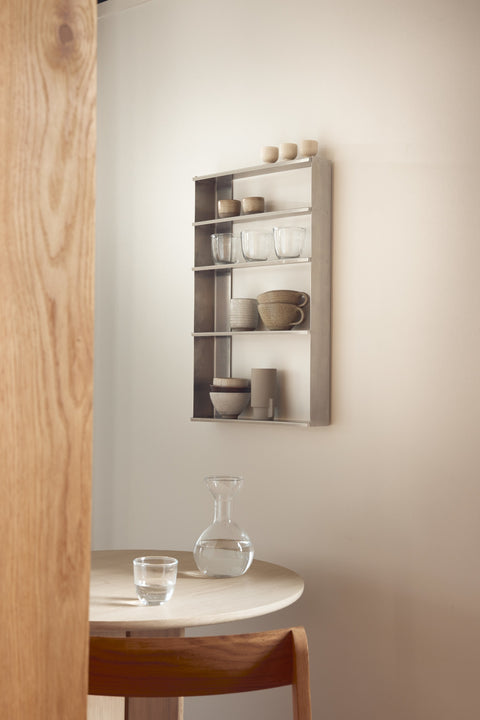 Form & Refine Taper Case, brushed stainless steel wall shelf, the Taper Case on a wall above a small round table, holding bowls and cups
