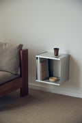 Form & Refine Taper Cube Box 34x35, brushed stainless steel wall cube, the Taper cube box on a living room wall beside the Icon Lounge Chair
