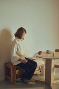 Form & Refine Trefoil Round Table Ø75, round oak dining table, person seated at the white oak round table on a Monolith side table, reading