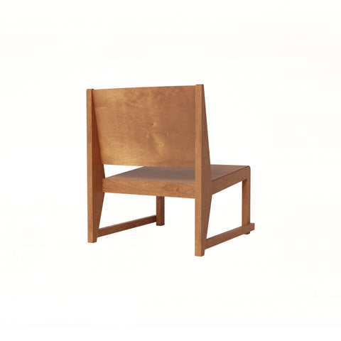 Frama Easy Chair 01 in Warm Brown Birch, low lounge chair with a wide flat back panel and sled legs, three quarter view on white
