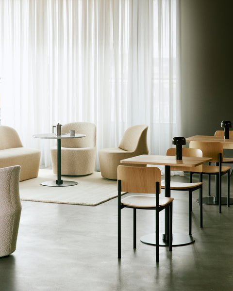Café setting with PLAN Chairs by Fredericia arranged around square tables with light filtering curtains in the background
