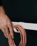 Pedestal Hook Mount in Pearl, steel accessory hook, a hand hanging a coiled cable on the hook