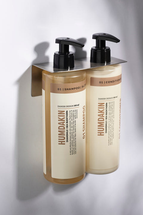 Humdakin 01 Conditioner, Chamomile & Sea Buckthorn, hair conditioner, shampoo and conditioner bottles in a wall-mounted holder on white tiles