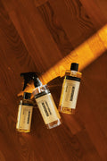 Humdakin Wood Cleaner, wood furniture and floor cleaner concentrate, bottle and spray bottle lying on a wooden table beside a broom handle