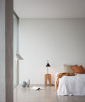 scandinavian minimal bedroom with oak end table and concrete floor