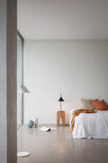 scandinavian minimal bedroom with oak end table and concrete floor